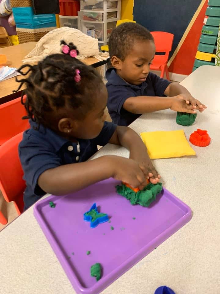 Two children playing with modeling clay at a table