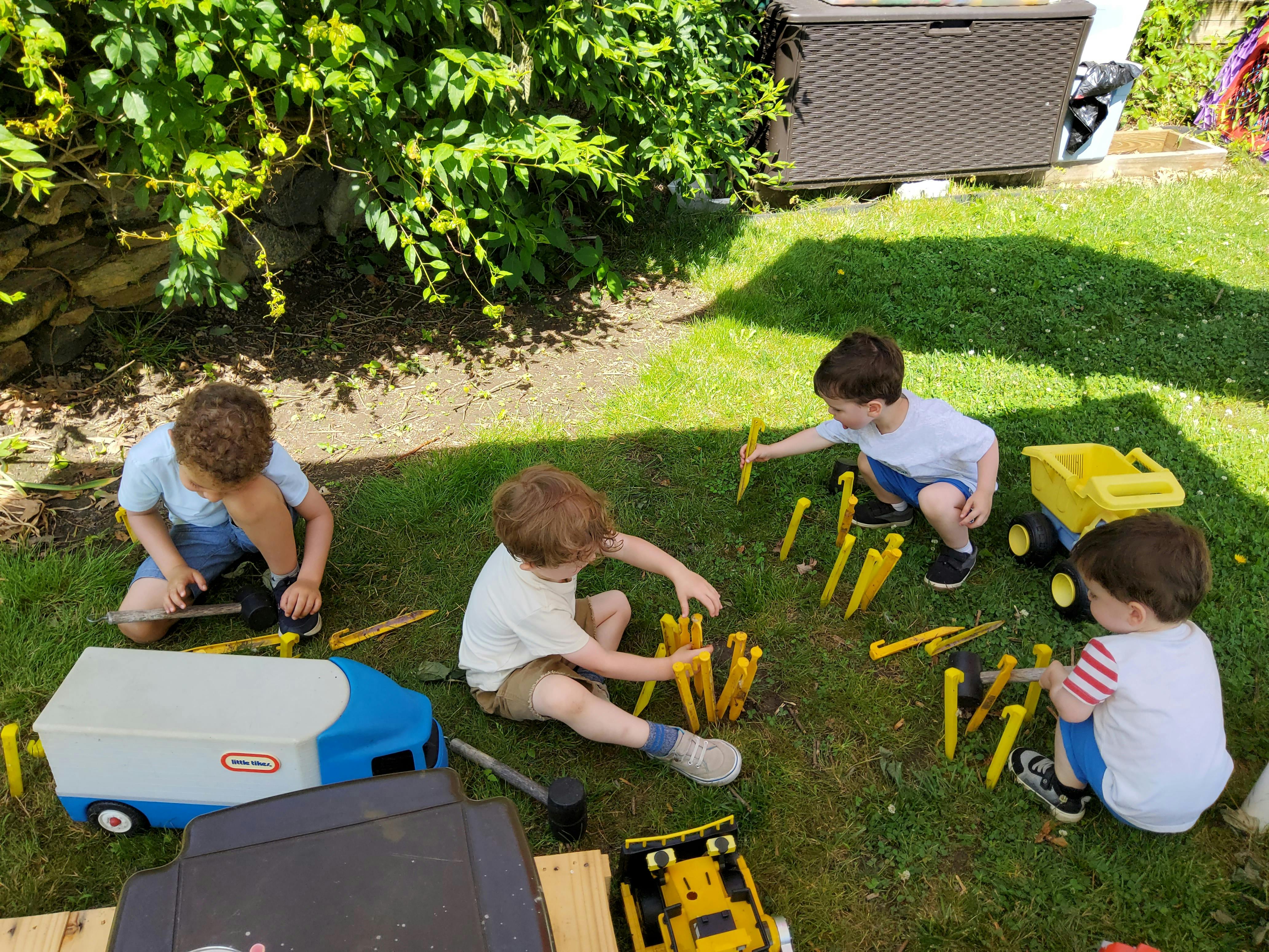 Four children playing with yellow plastic toys on grass