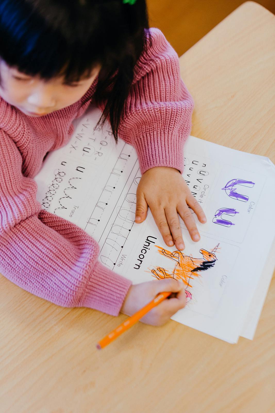 Child coloring a unicorn in a workbook