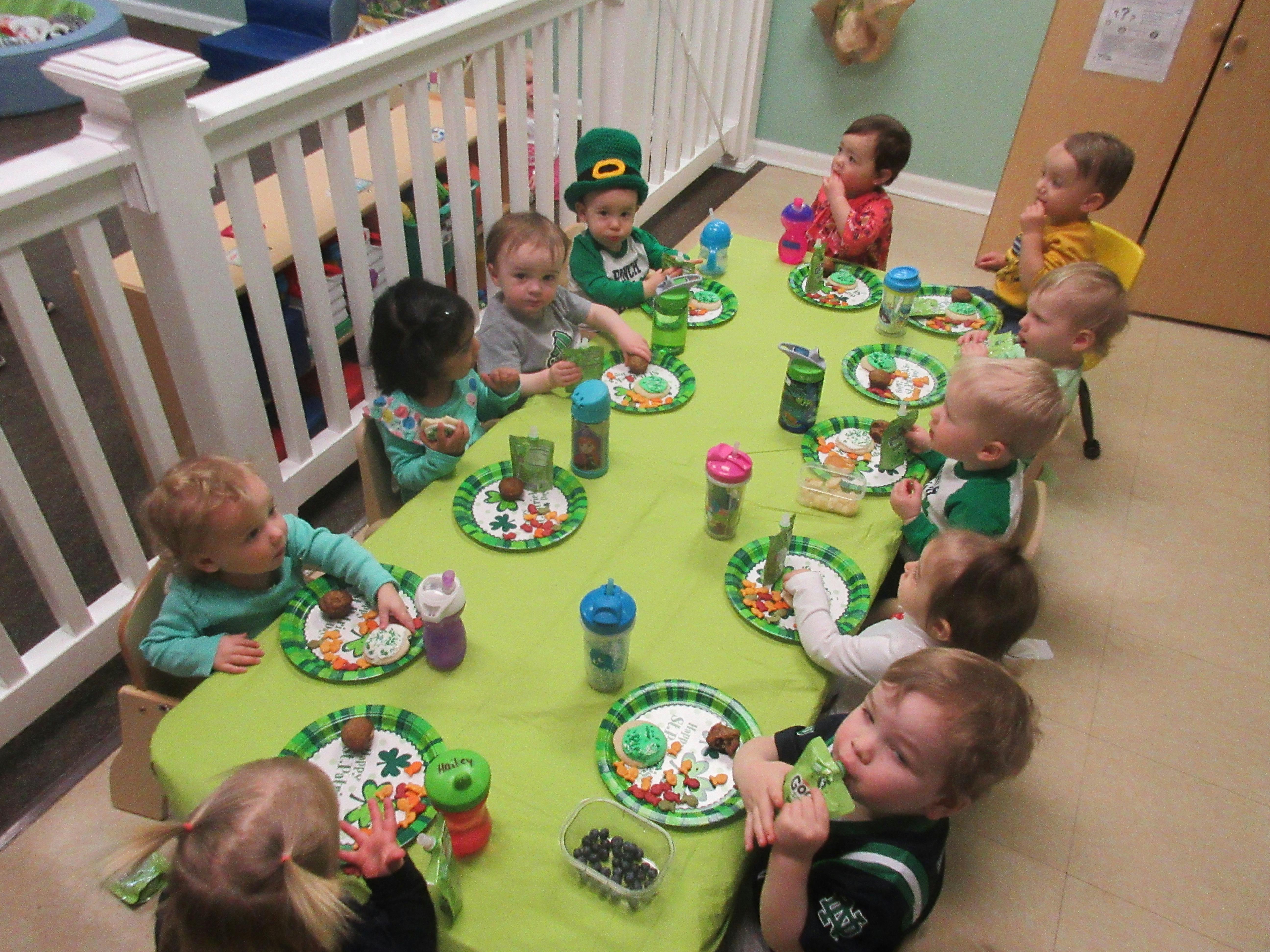 Multiple children sitting around a table with plates and eating