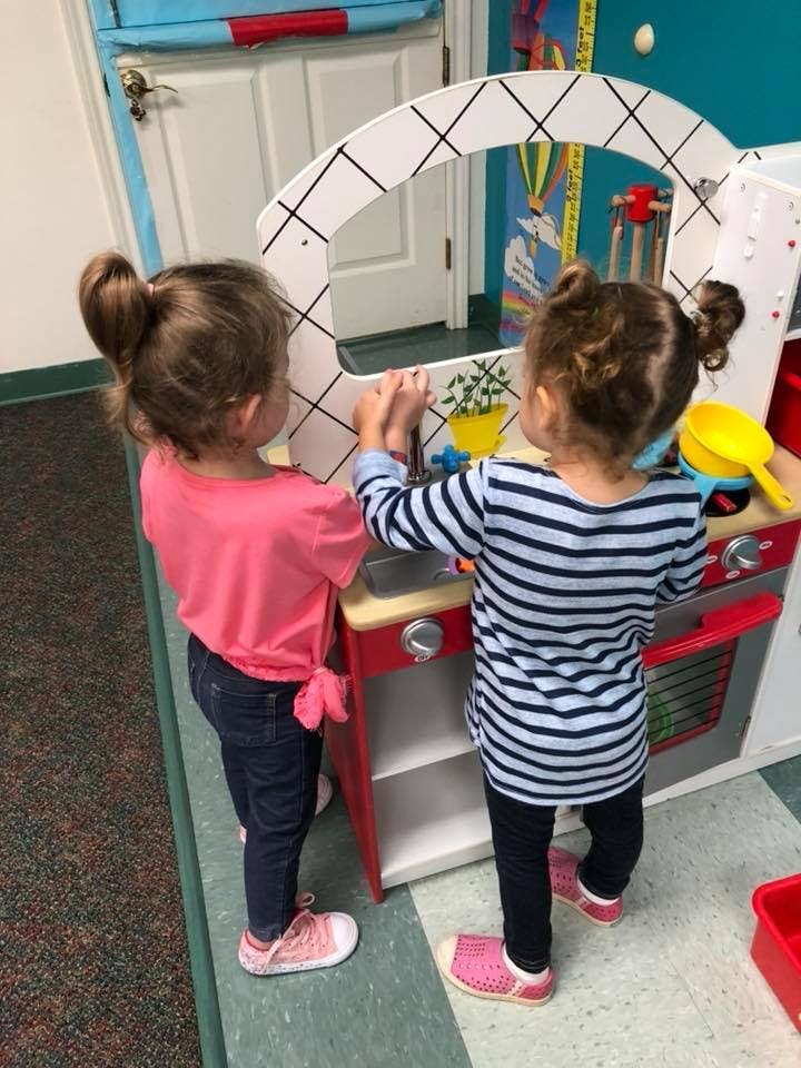 Two children playing with a toy kitchen set