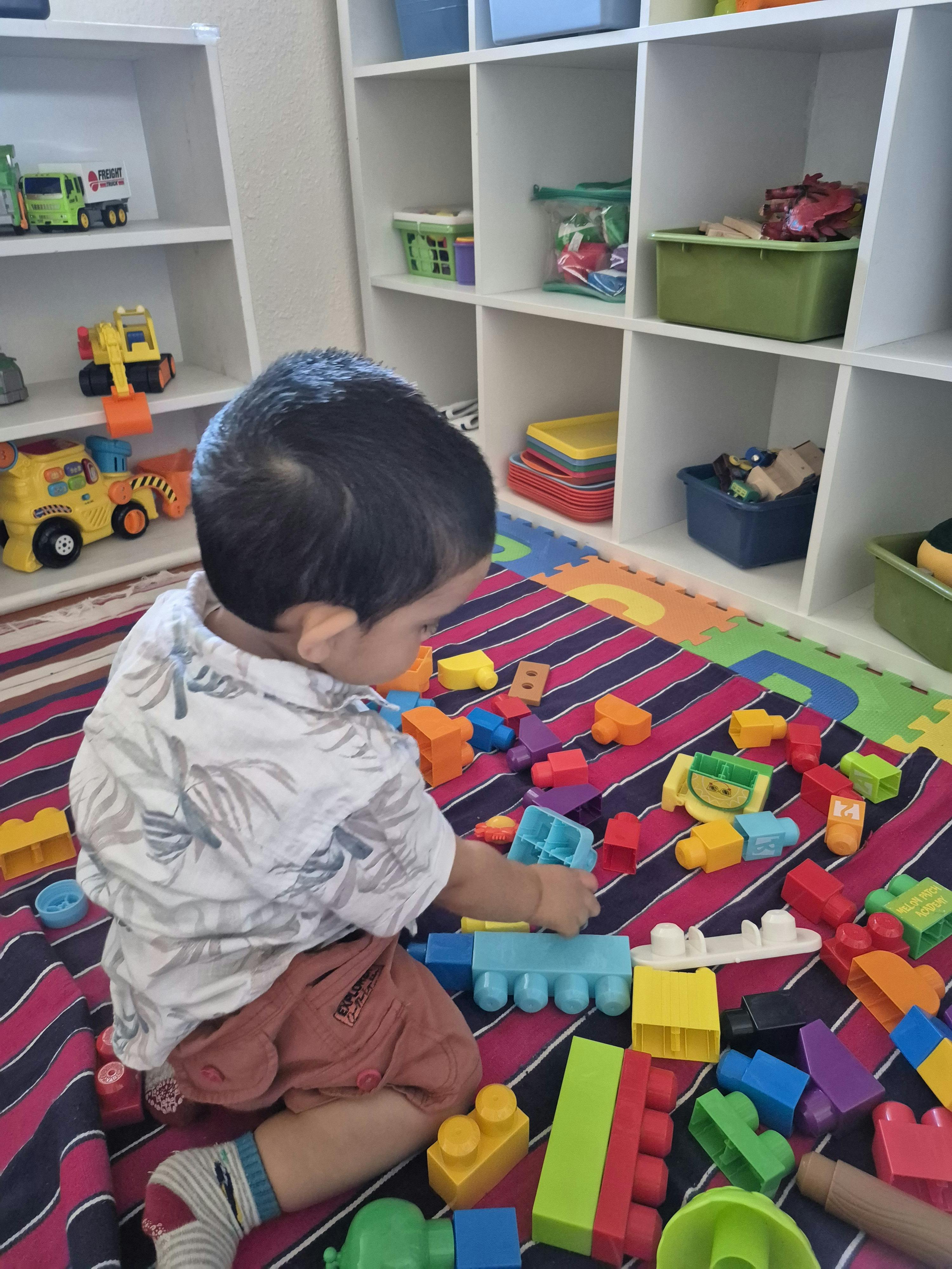 Child playing with colorful building blocks on a mat