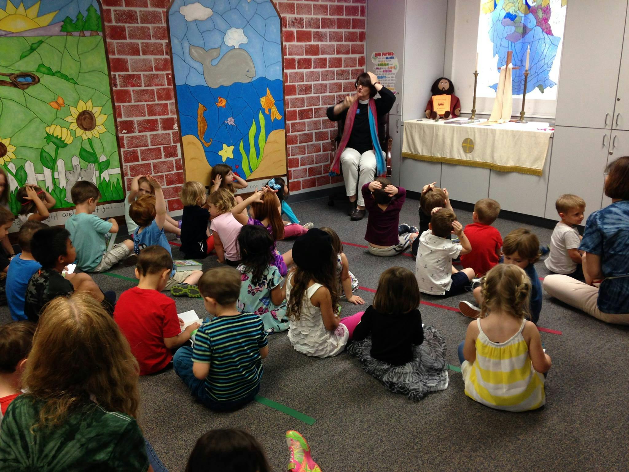 Adult speaking to a group of children sitting on the floor