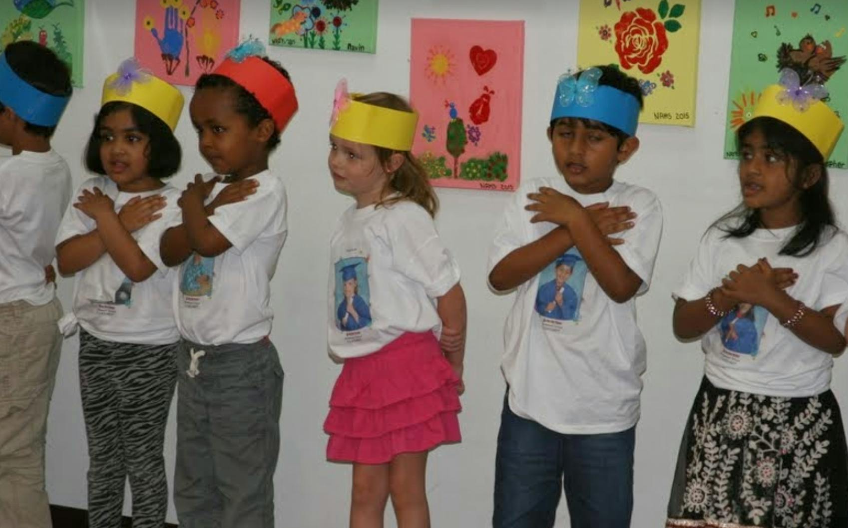 Children in paper crowns with hands crossed over chests