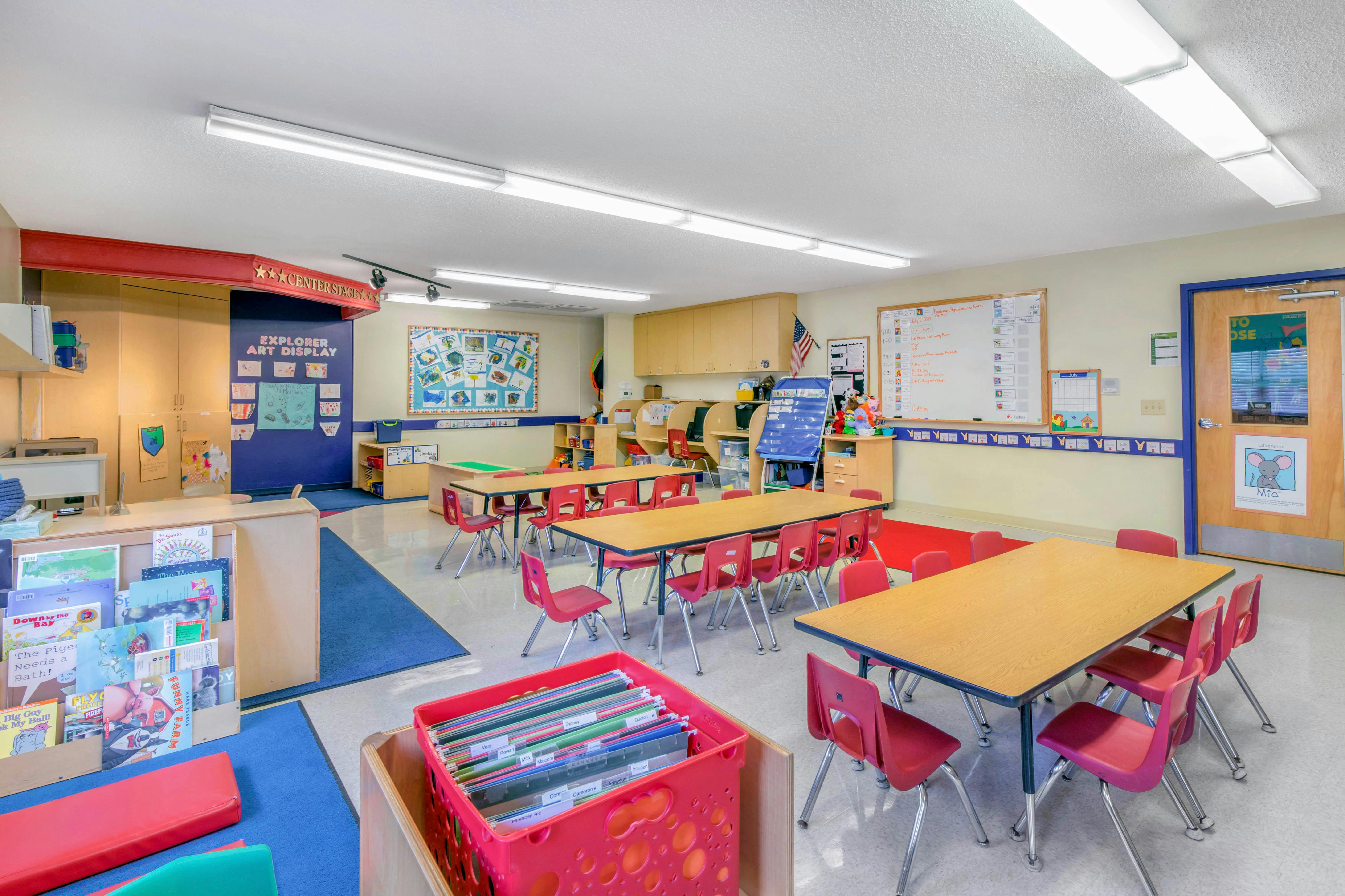 Classroom with small tables and chairs, book display, art display on wall