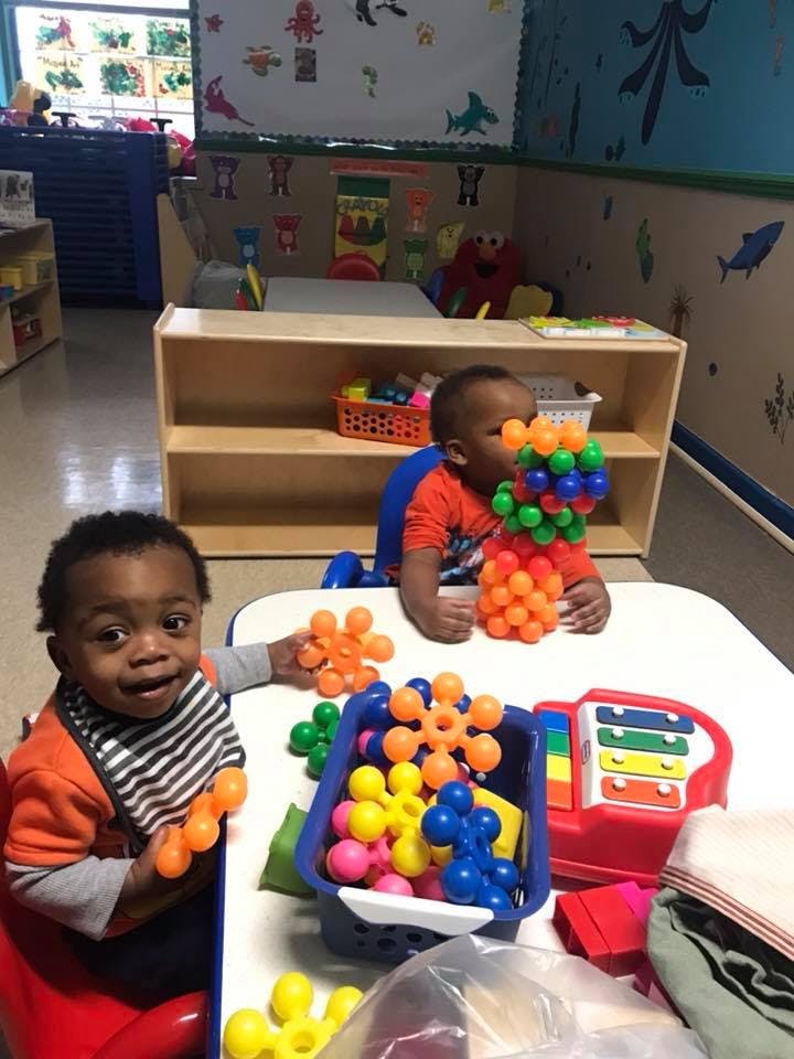 Two children playing with colorful interlocking toys at a table in a classroom
