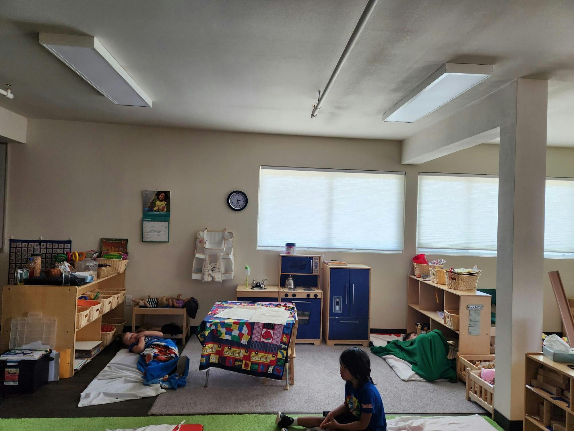 Child sitting on the floor in a classroom with play furniture