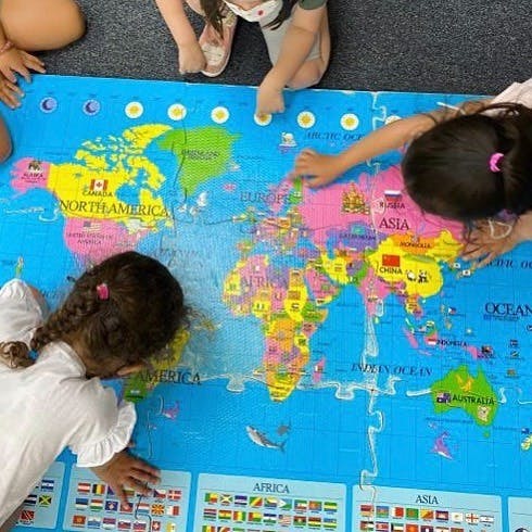 Children playing with a large world map puzzle