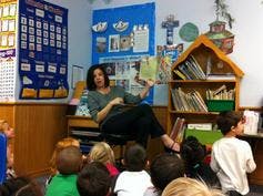 Person reading a book to children in a classroom