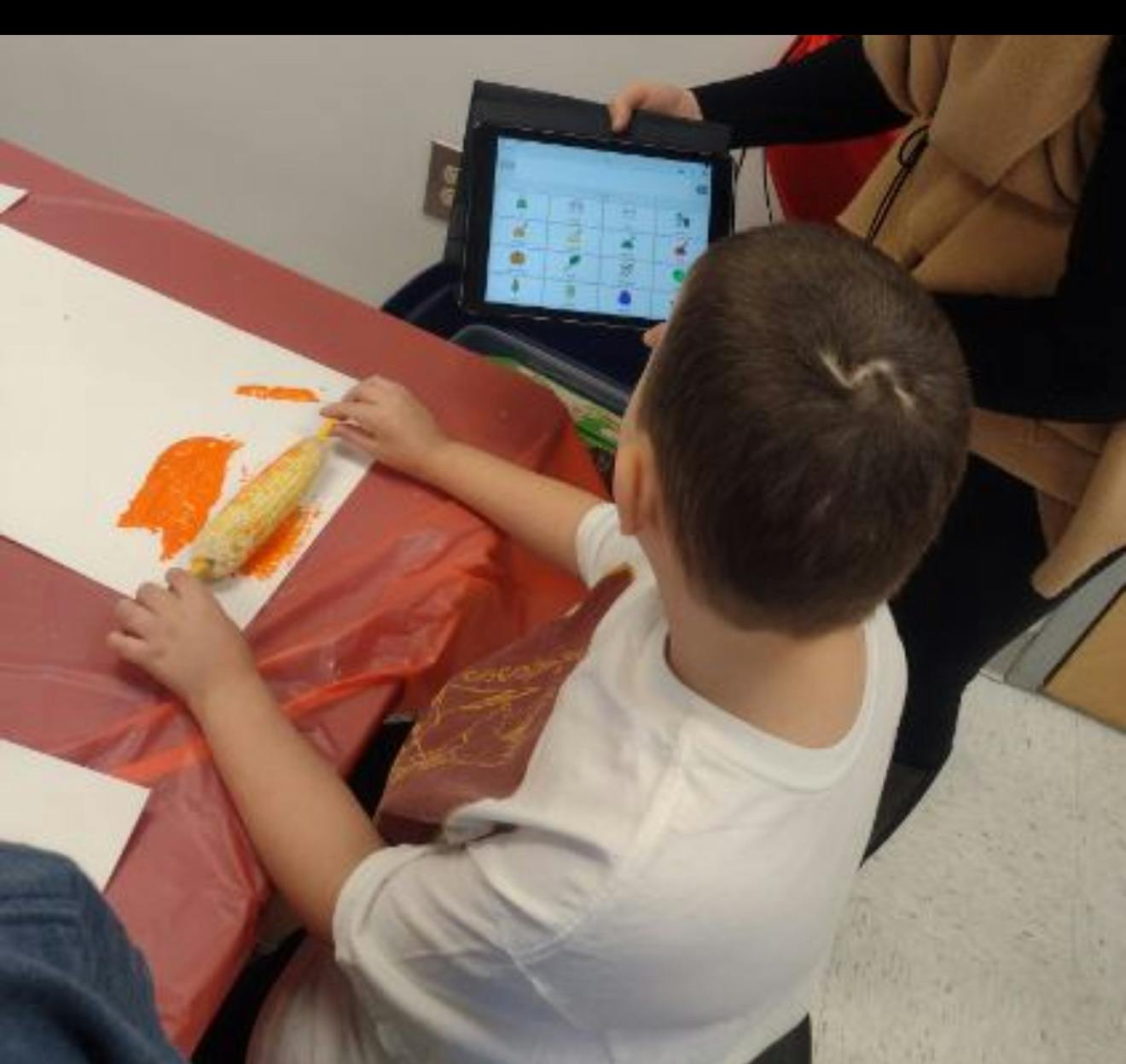 Child painting with corn on a white paper