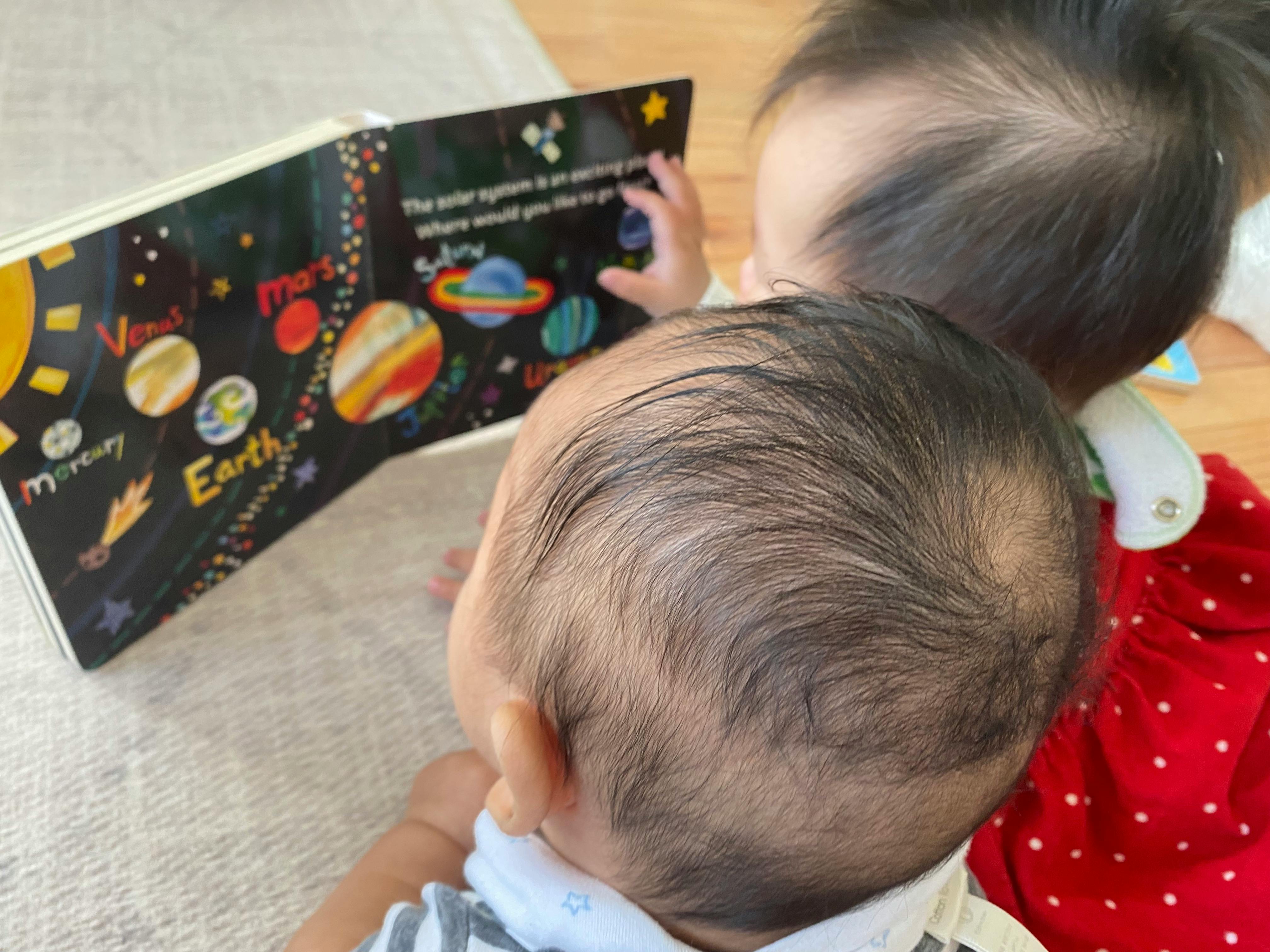 Two children looking at a book about planets