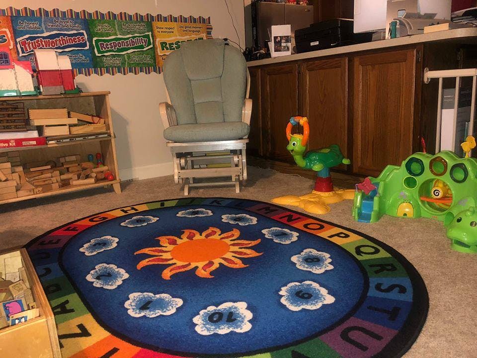 Playroom with a sun and clouds rug, rocking chair, and toys