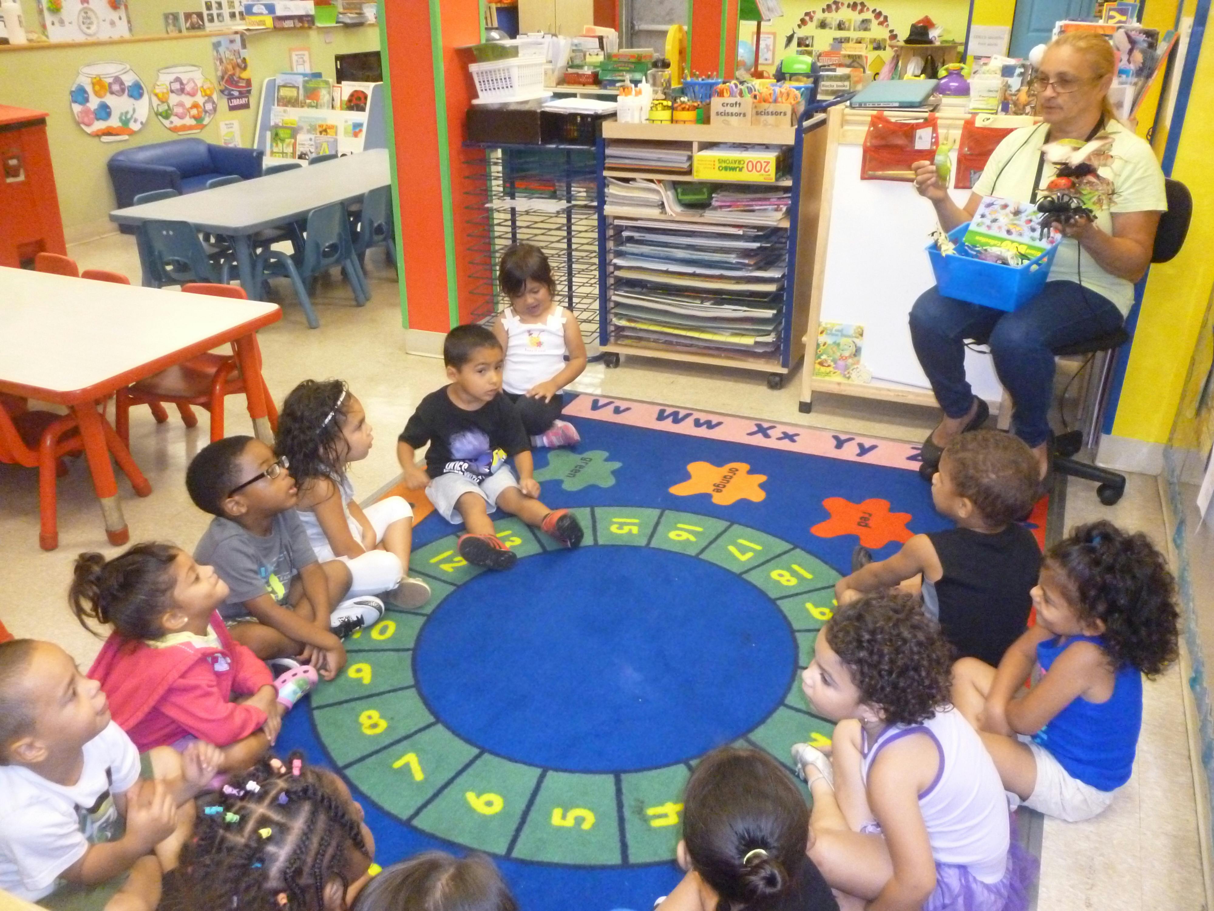 Adult teaching a group of children sitting on a rug in a classroom