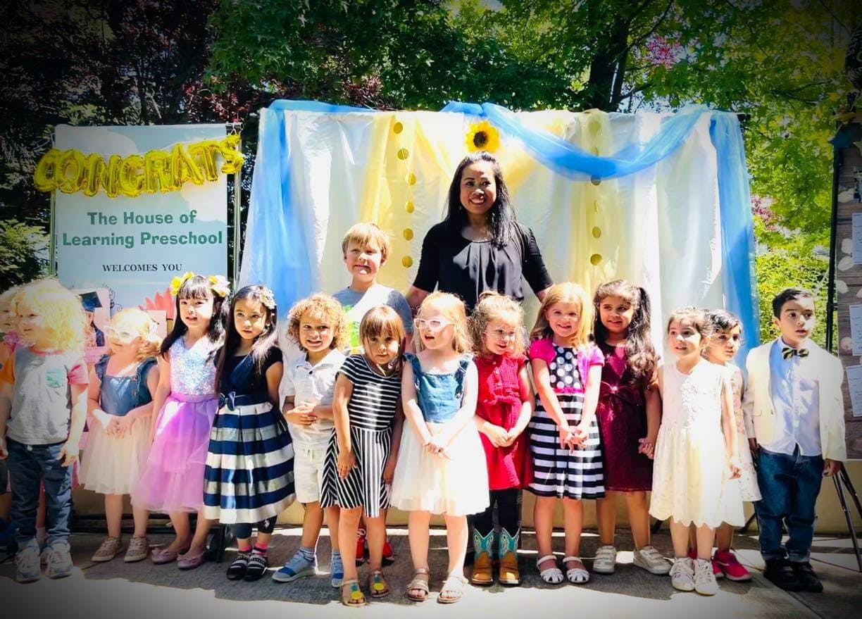 Adult and group of children standing in front of a decorated backdrop