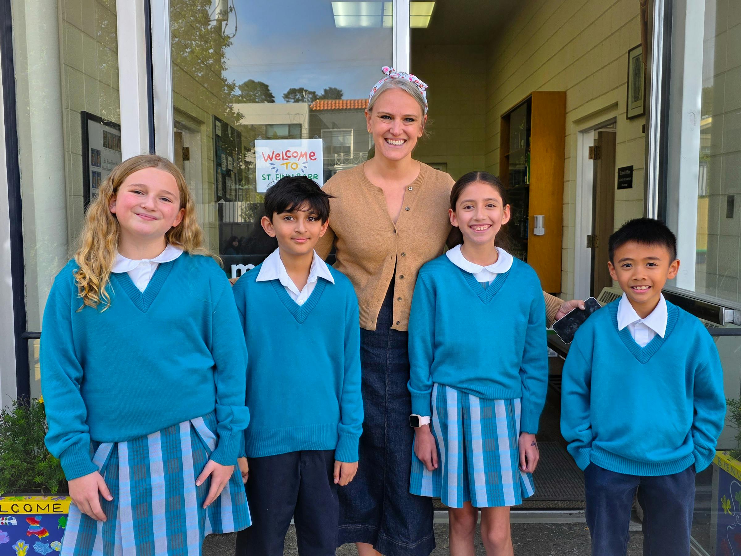 Adult and four children in school uniforms standing together