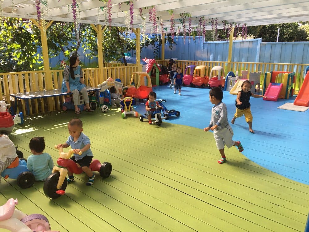 Children playing on tricycles and running in an outdoor play area