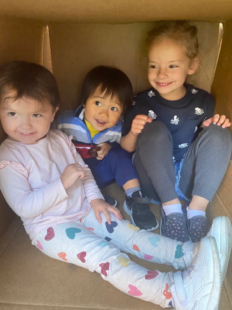 Three children sitting together in a box