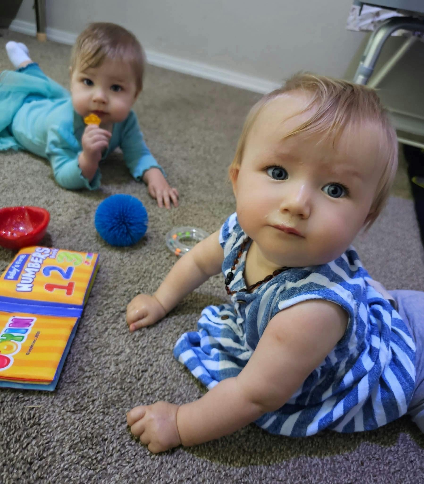 Two children crawling on a carpeted floor with toys