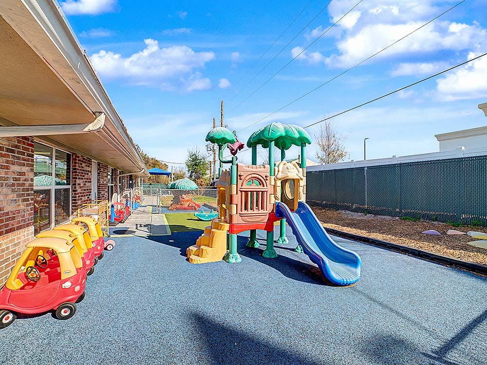 Outdoor playground with colorful play structures, slides, and toy cars