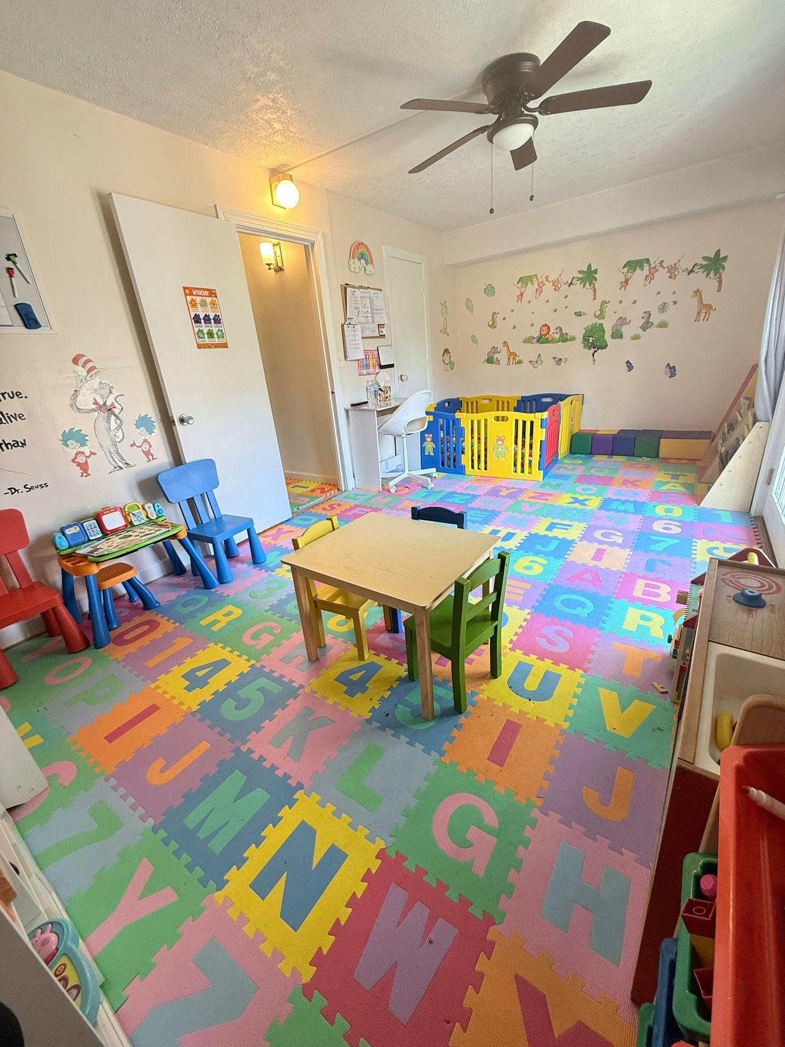 Playroom with alphabet floor mats, small tables, and chairs