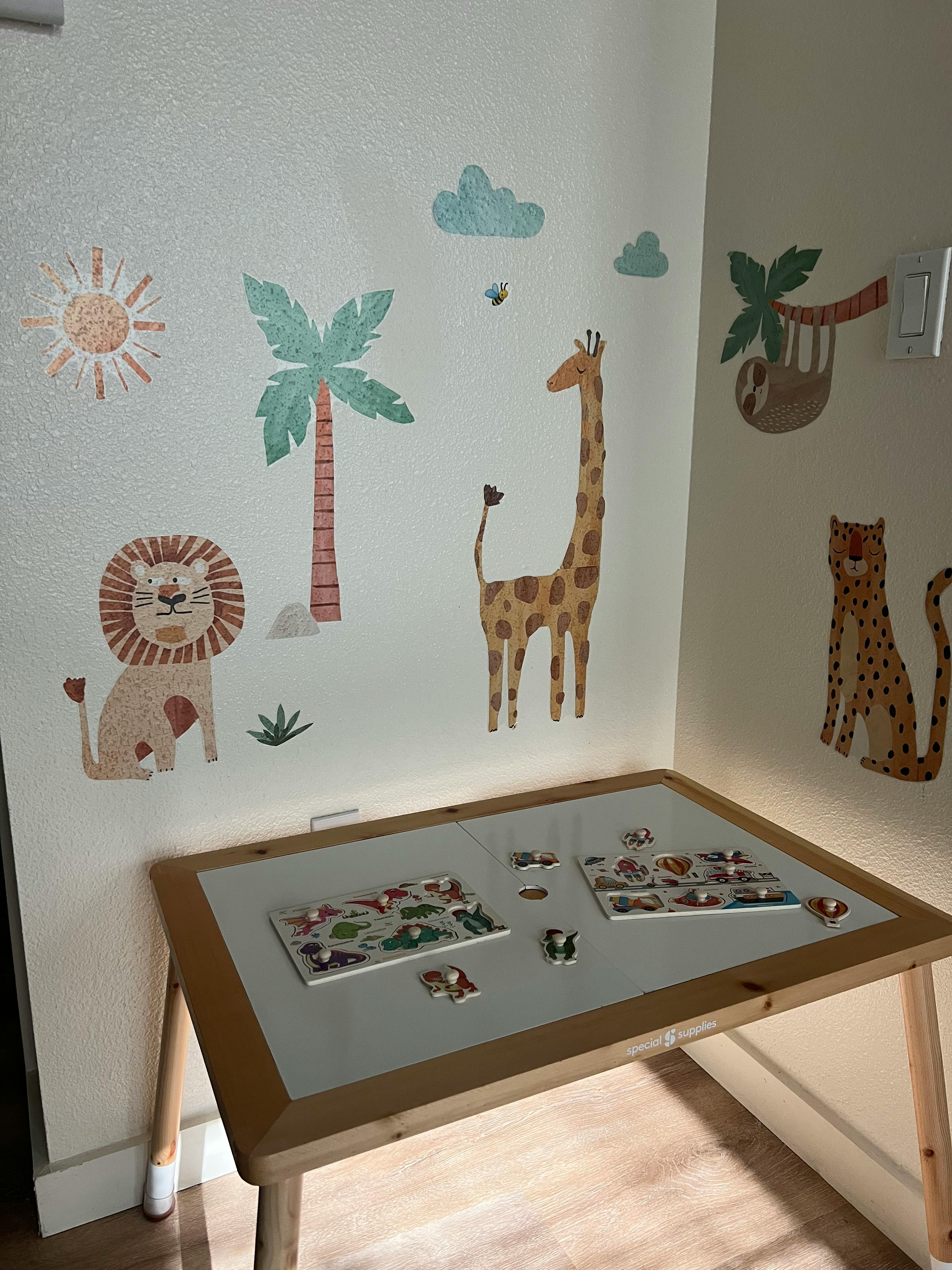 Wall decals of safari animals and plants above a table with puzzles