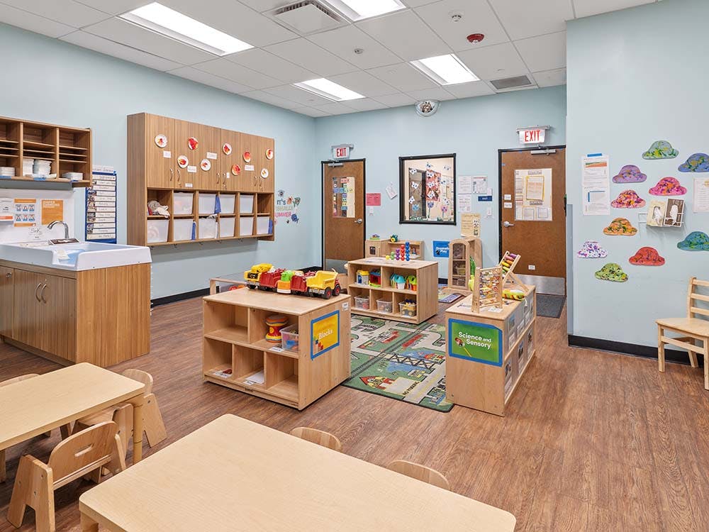 Classroom with child-sized tables, changing station, storage cubbies, and toys