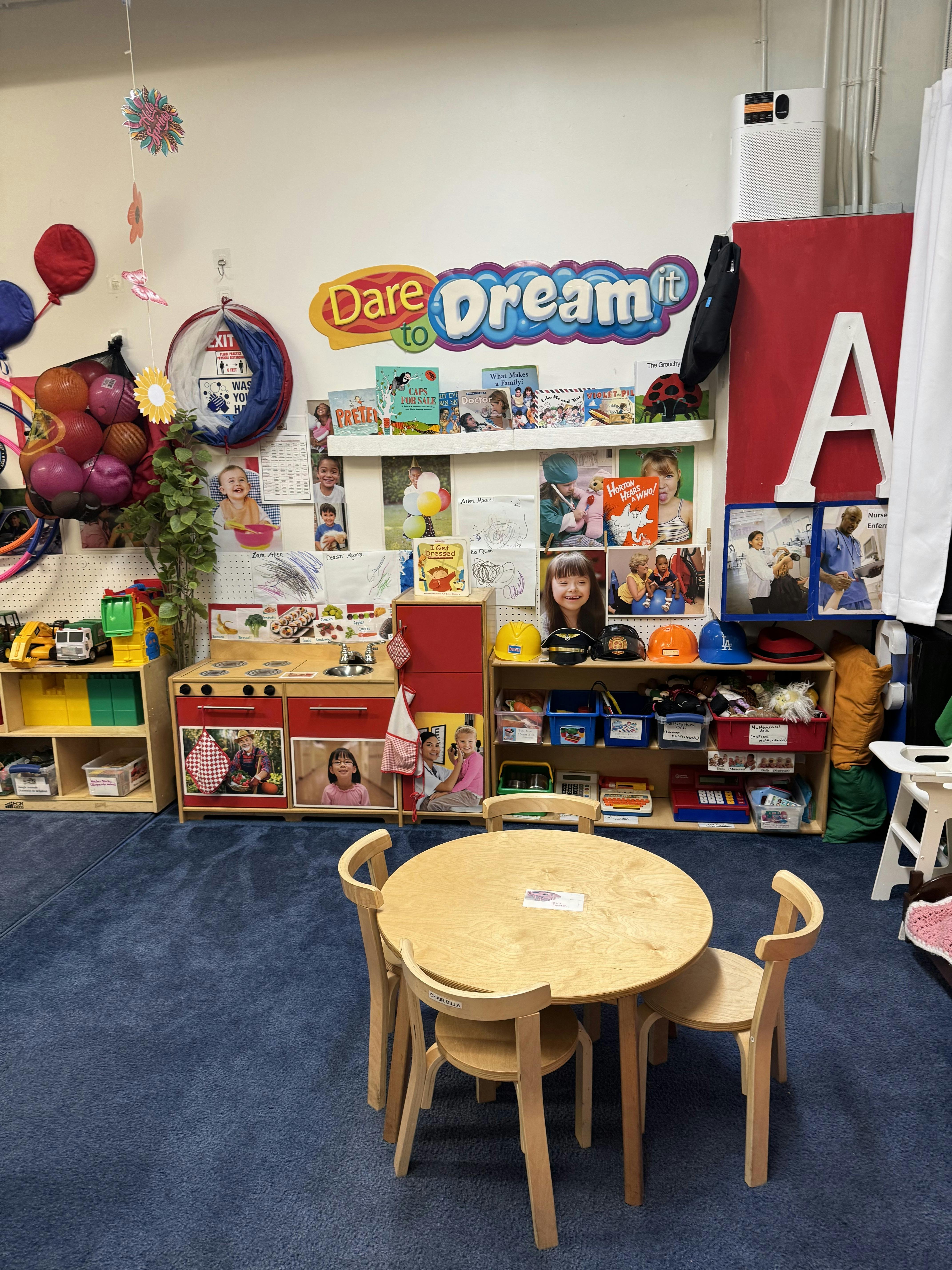 Children's play area with a small table and chairs, play kitchen, and shelves