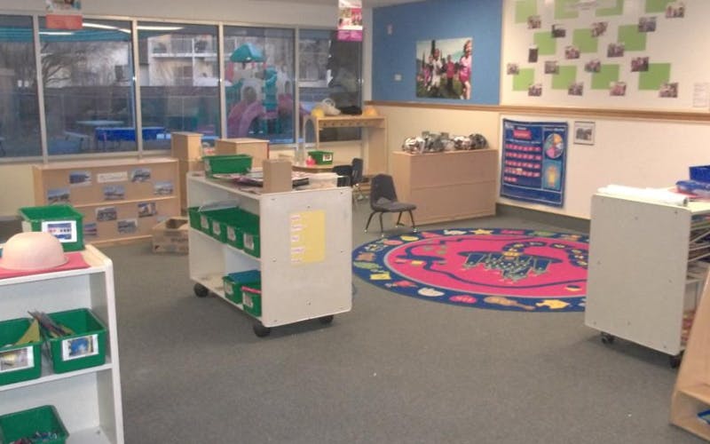 Empty classroom with children's furniture, supplies, and a colorful rug