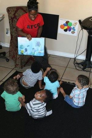Person reading a book to several children sitting on the floor