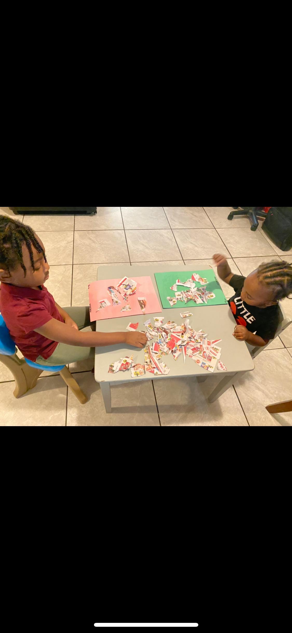 Two children sitting at a table playing with puzzle pieces