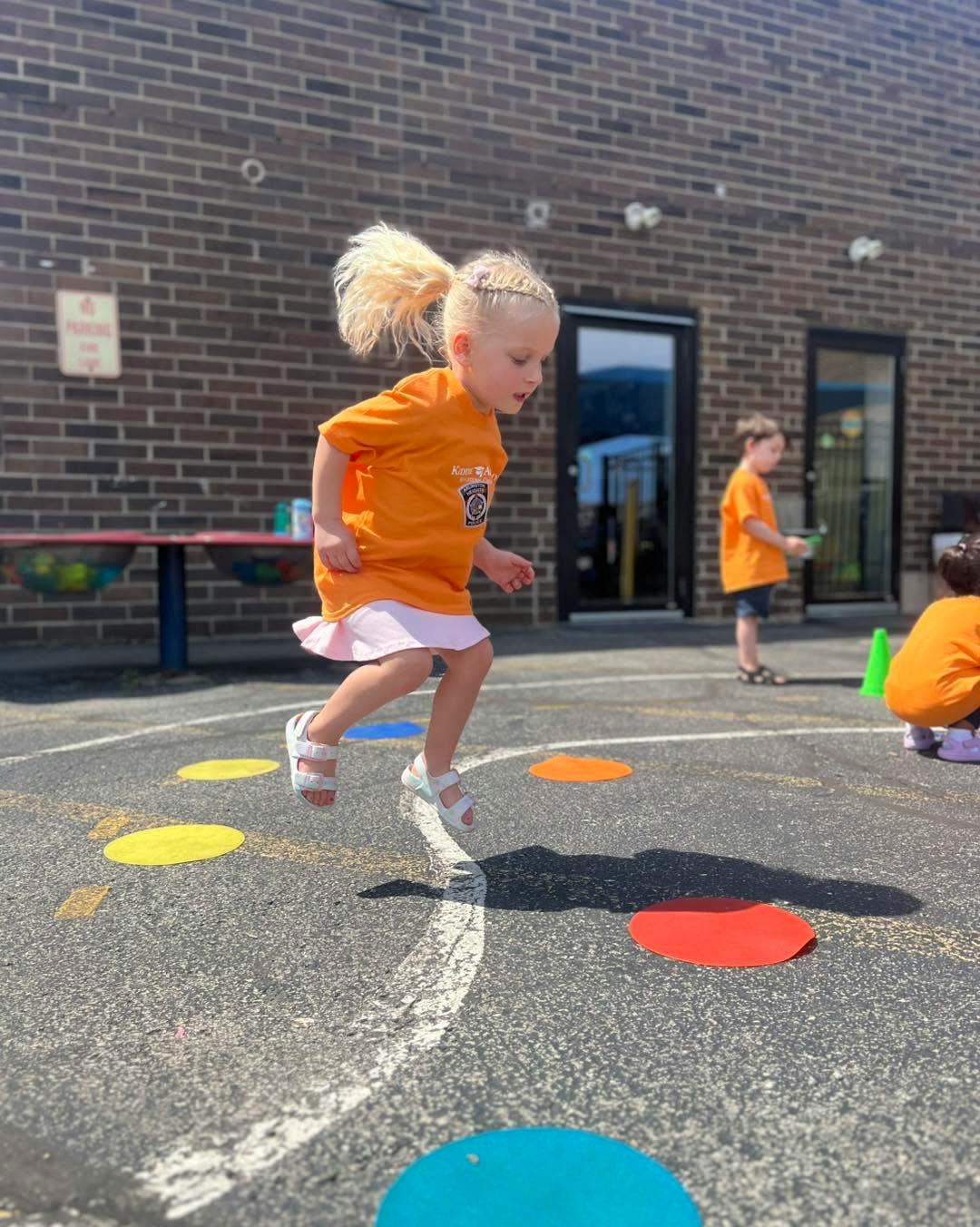 Child jumping over colorful markers on an outdoor playground