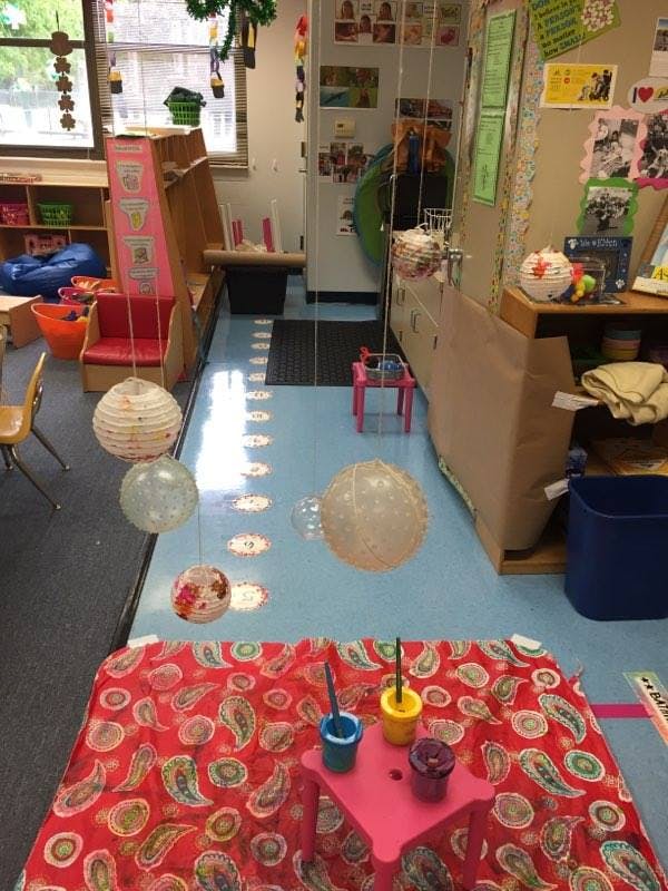 Classroom with red patterned rug, small pink table, and hanging decorations