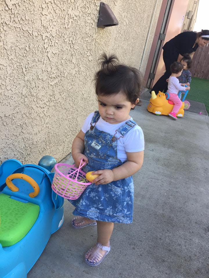 Child holding a pink basket and a yellow object