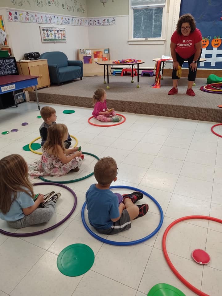 Adult and children sitting in hoops in a classroom