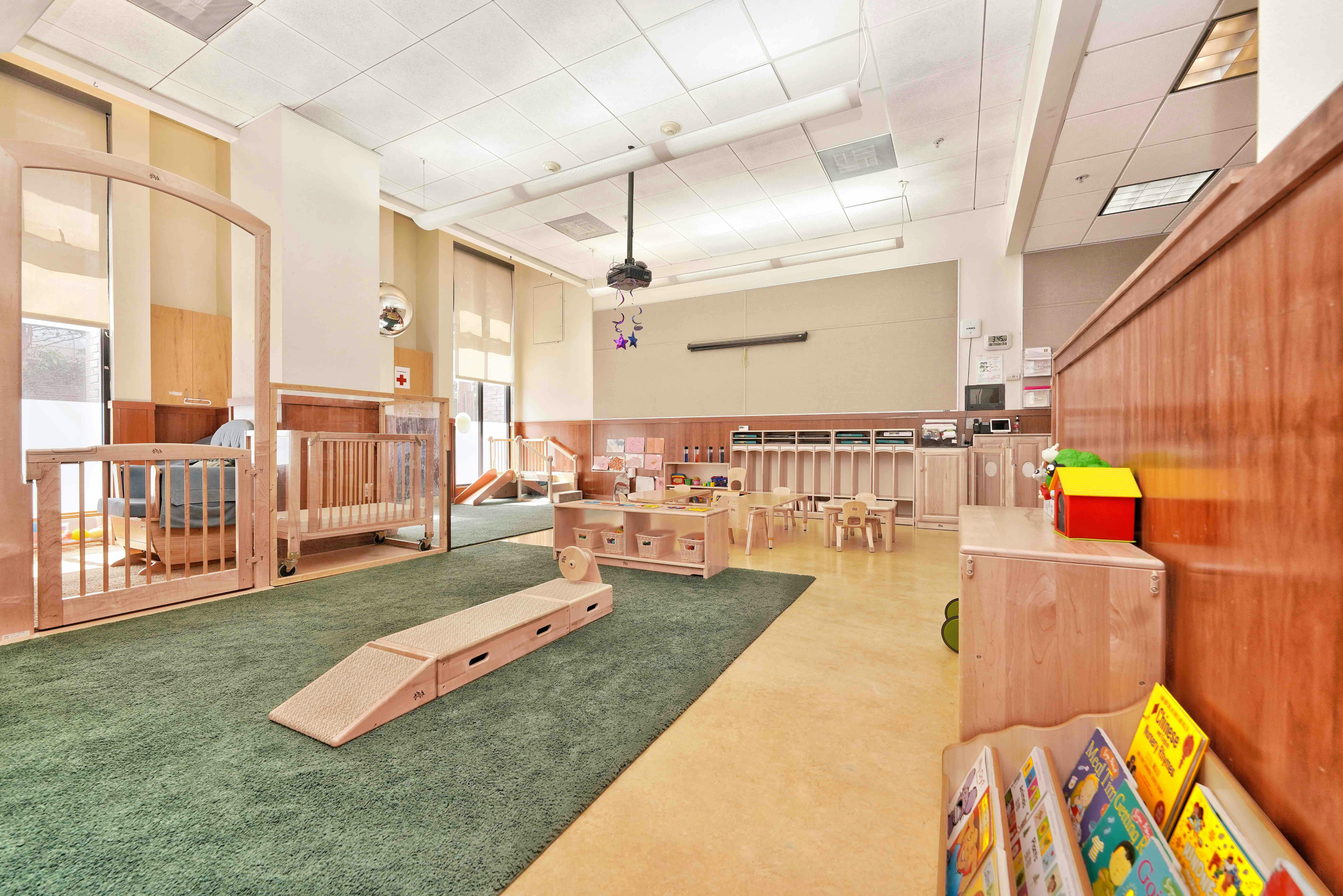 Childcare classroom with infant cribs small tables and play equipment