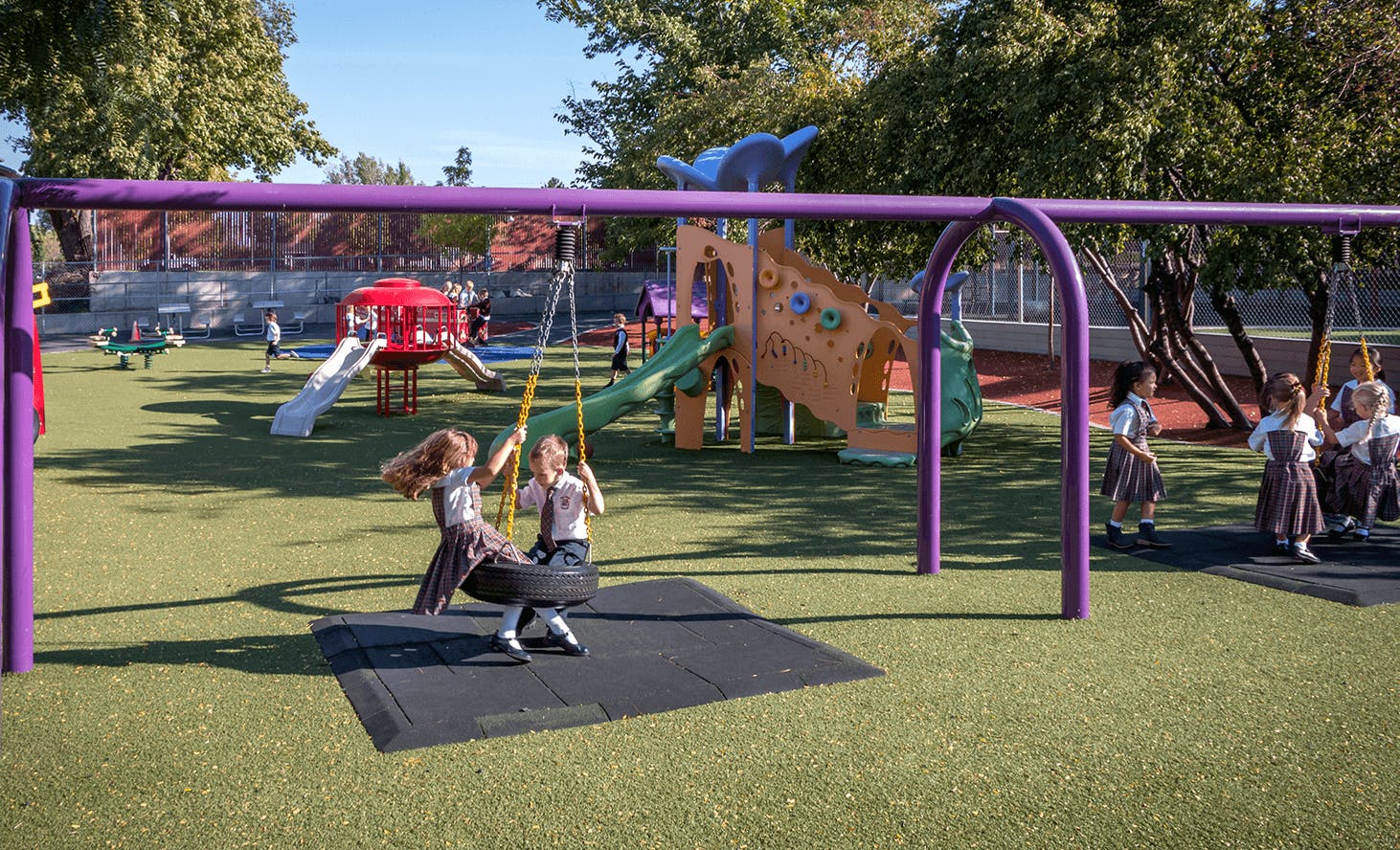 Two children on a tire swing on a playground