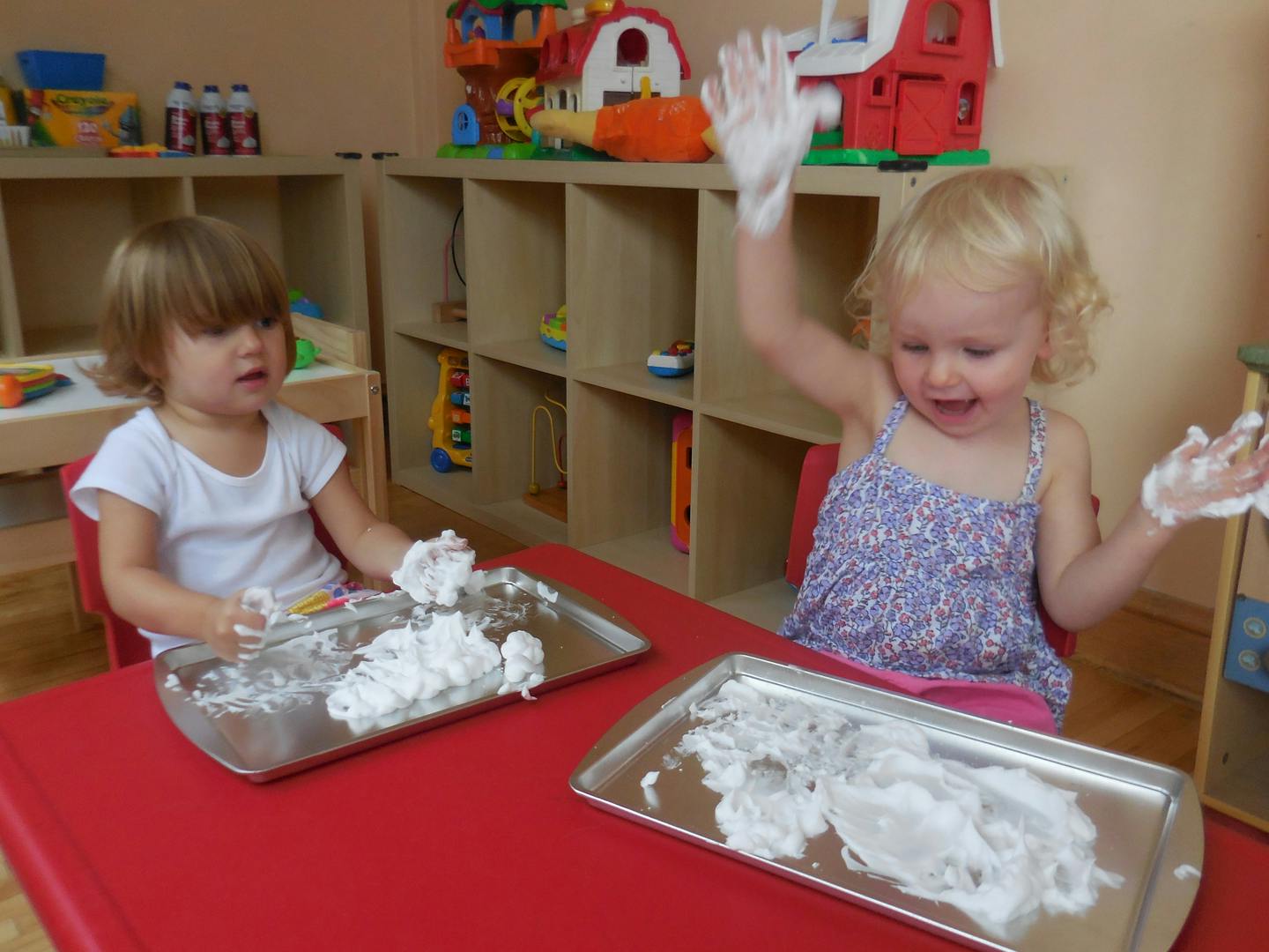 Two children playing with shaving cream at a table