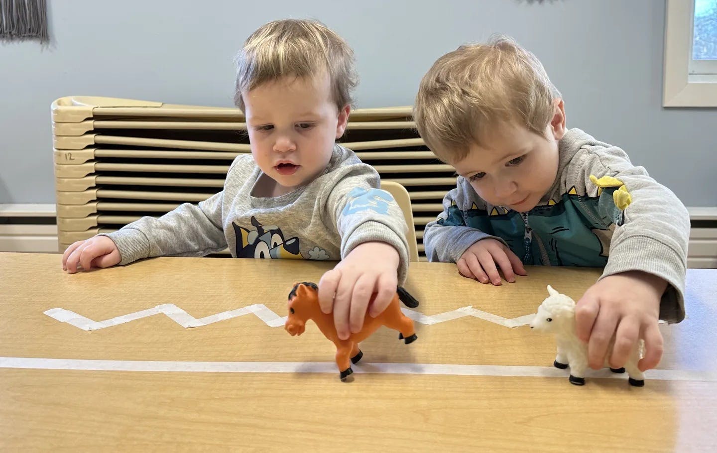 Two children playing with animal toys on a table