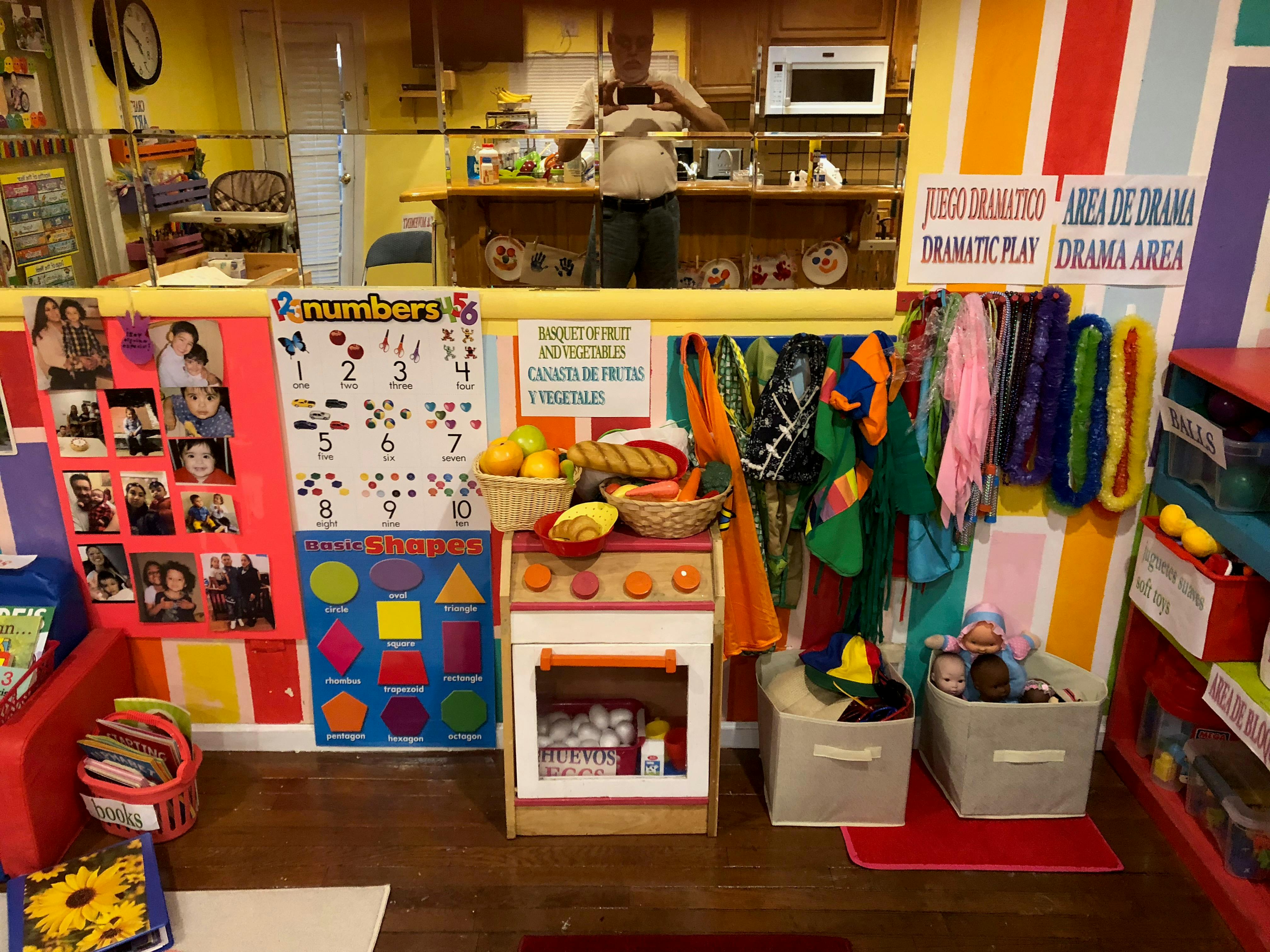 Play kitchen with baskets of fruit and bread, colorful scarves, and educational posters