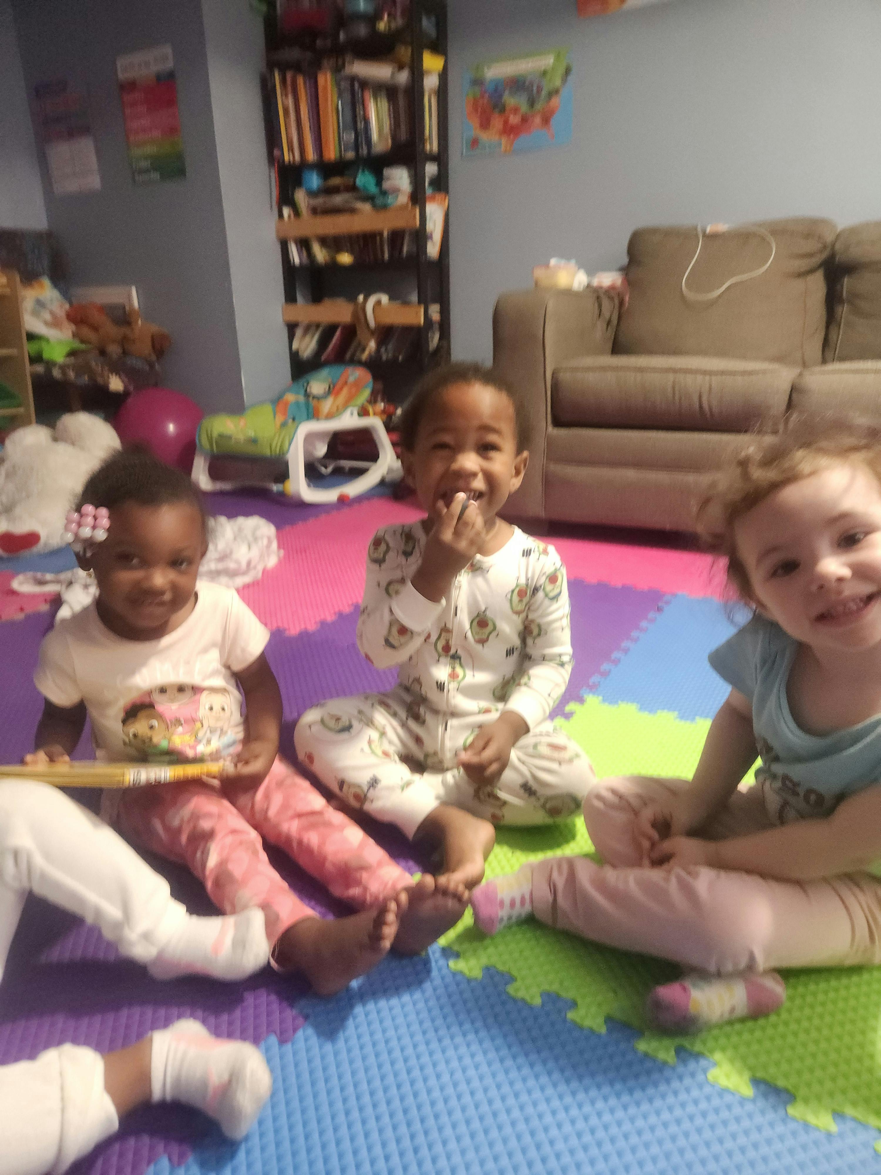 Three children sitting on a colorful mat