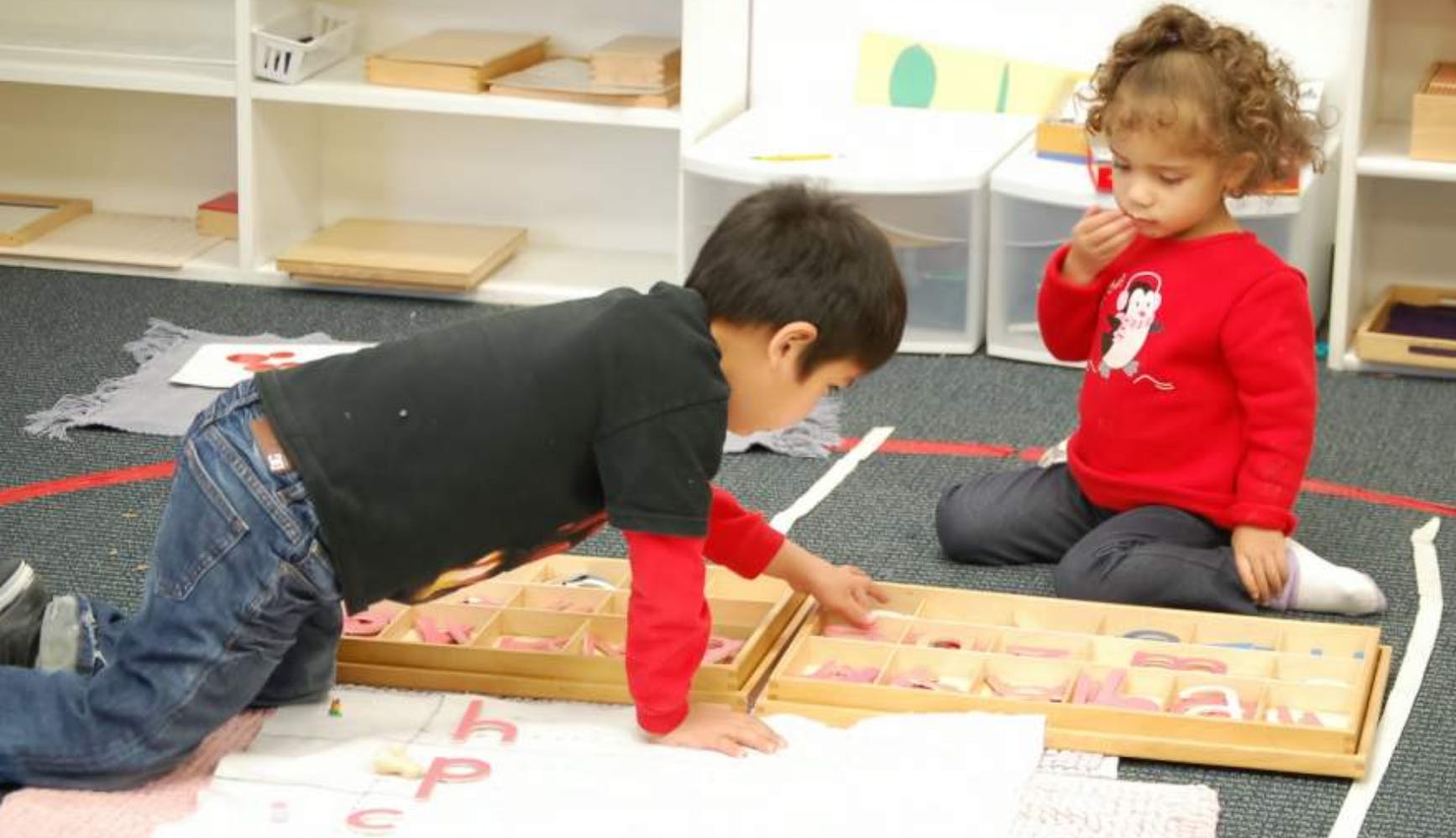 Two children playing with wooden learning materials on the floor