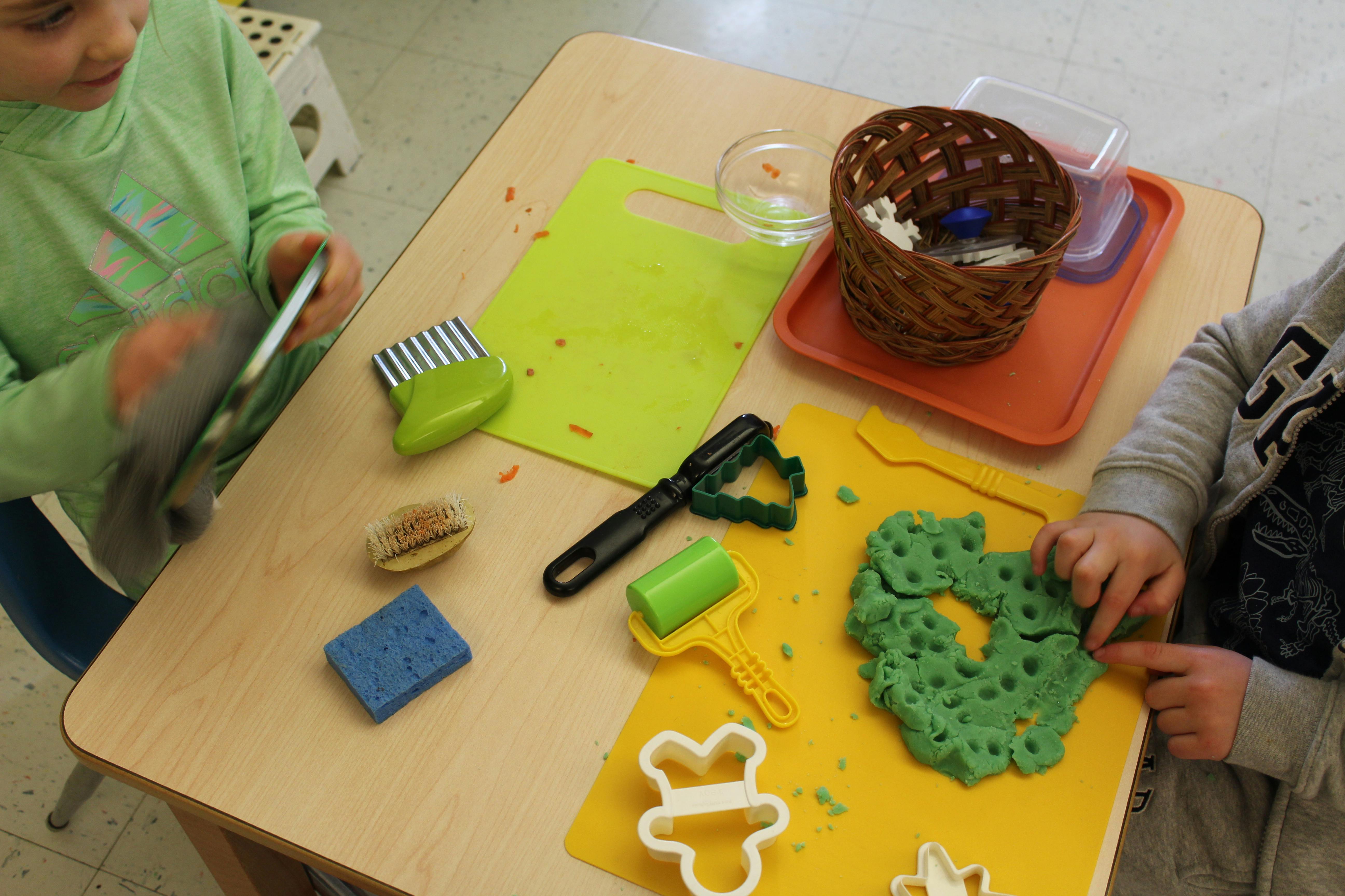 Children using tools and playdough at a table