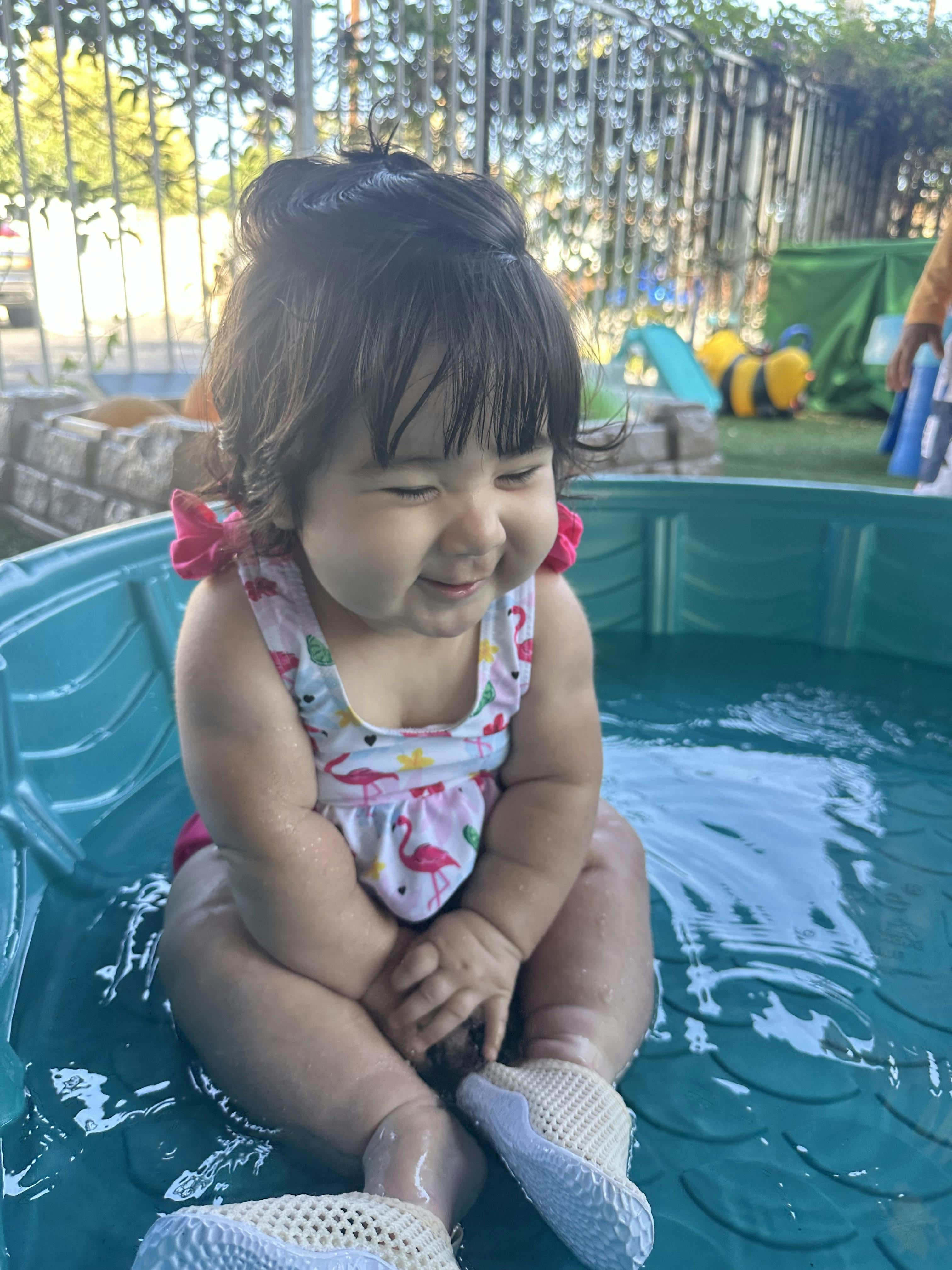 Child in a swimsuit sitting in a kiddie pool