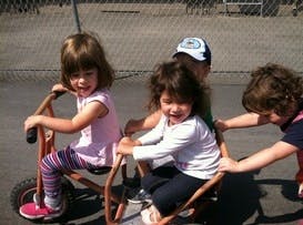 Three children riding tricycles outdoors