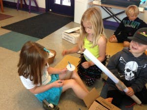 Three children sitting on the floor making crafts