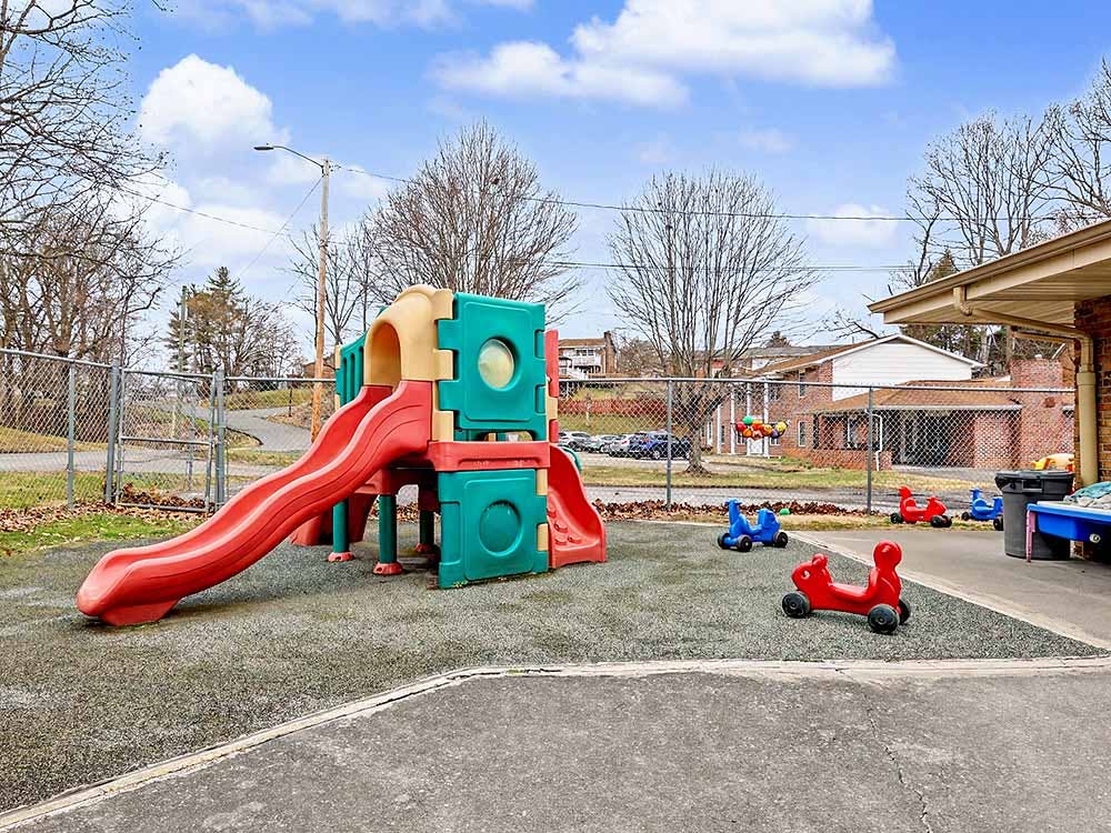 A colorful plastic playground structure with a slide on rubber ground