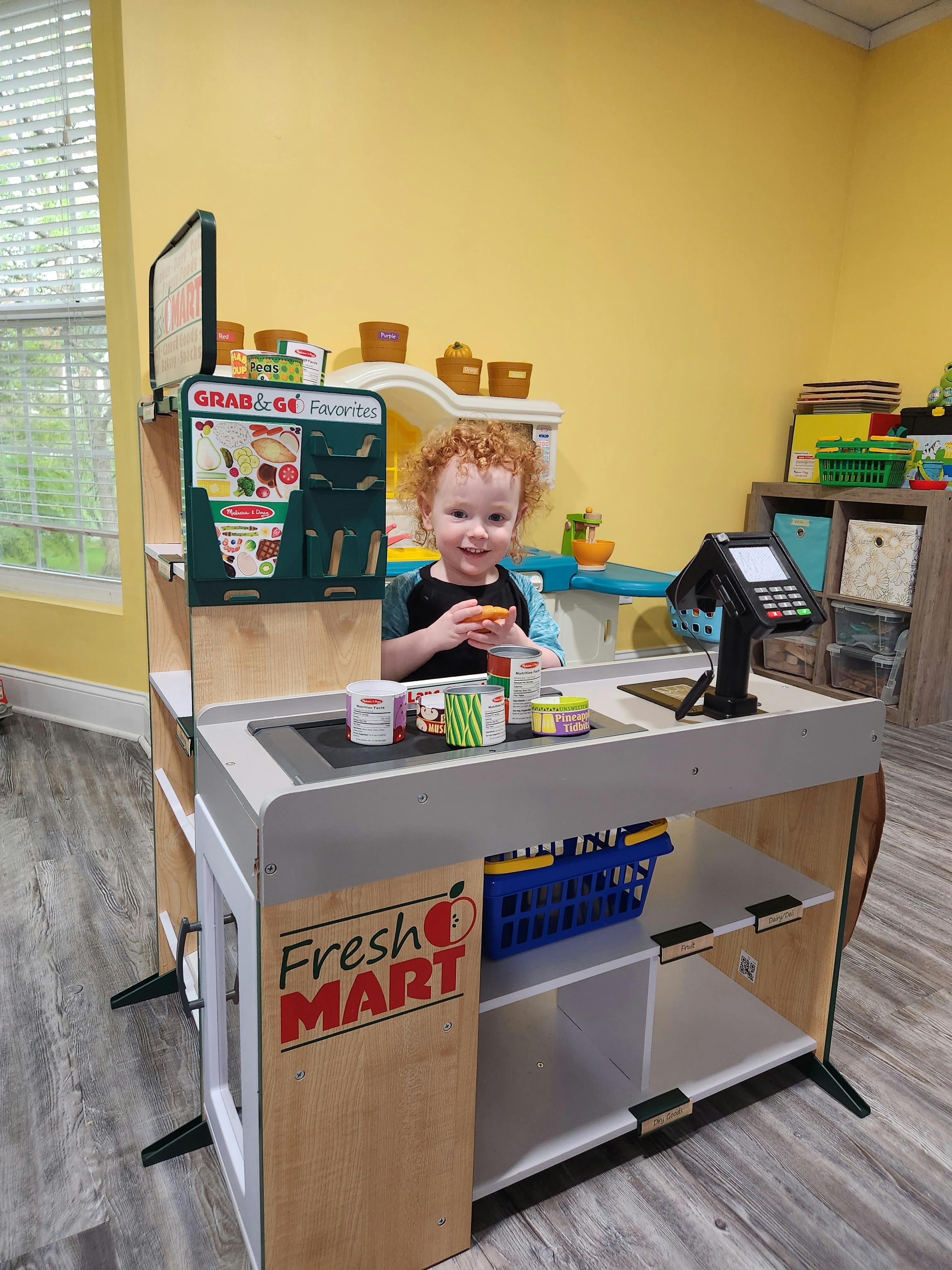 Child playing at a toy grocery store counter