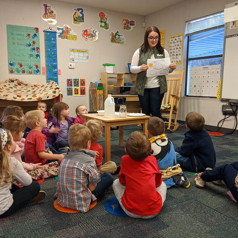 Adult person reading to a group of children in a classroom