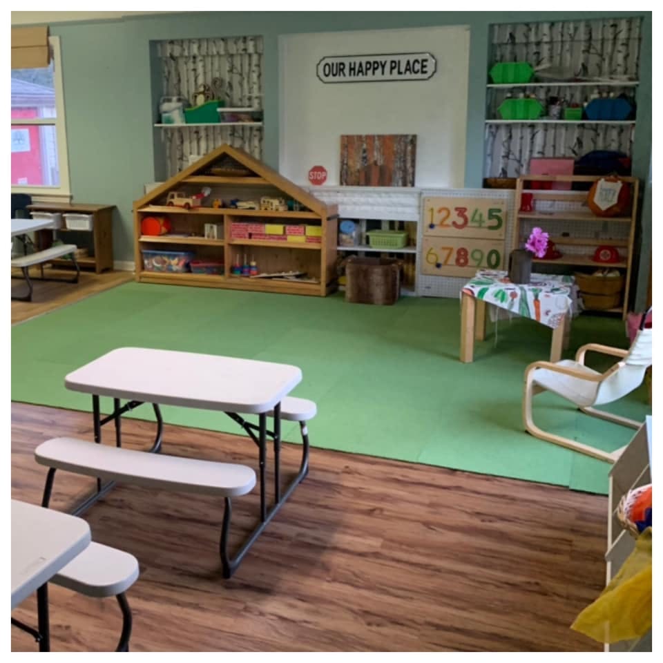 Children's play area with small tables and shelves of toys
