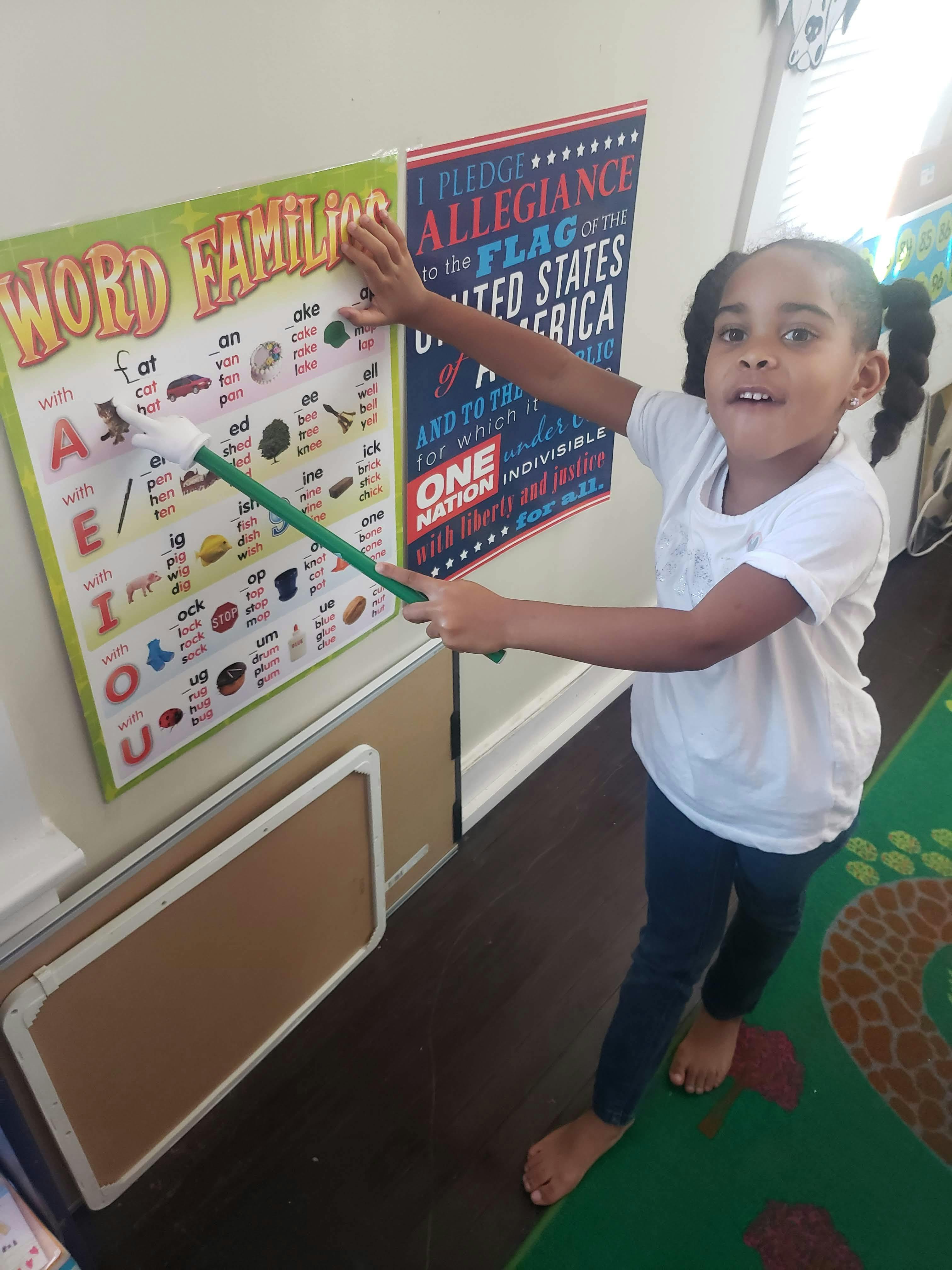 Child pointing to a "Word Families" chart with a pointer
